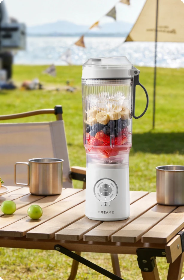 Batidora Dreame Portable Blender diseño sin cables en mesa de picnic preparando bebidas de frutas al aire libre